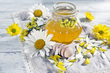 Honey and flowers on napkin on wooden background