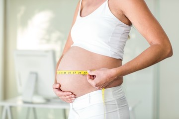Midsection of woman measuring belly