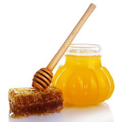 Pot of honey, wooden dipper and honeycomb isolated on white