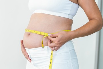 Mid section of woman measuring her waist