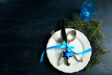 Empty plate, cutlery, napkin and glass on rustic wooden background. Christmas table setting concept