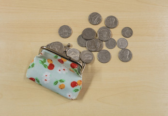 Coins with open money bag on wood desk background