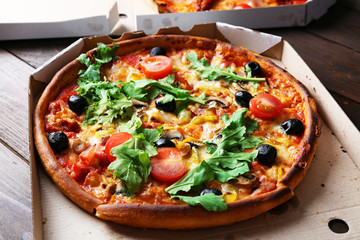 Pizza in box on wooden table closeup