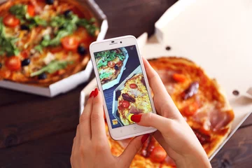 Fototapeten Woman taking a photo of pizza with the smartphone © Africa Studio