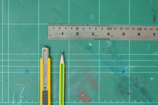 Cutter , wood pencil and ruler on old green rubber pad background