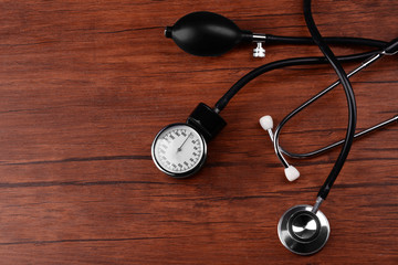 Blood pressure meter and stethoscope, on wooden background