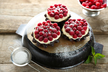 Sweet cakes with raspberries on wooden table background