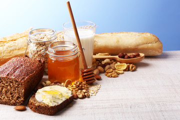 Healthy breakfast with bread, honey, nuts on table, on colorful background. Country breakfast concept