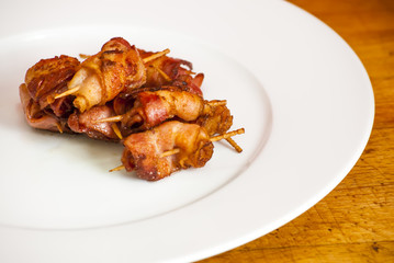 Rolls of slices of cooked bacon subject with a toothpick