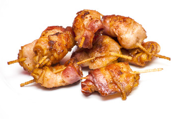 Rolls of slices of cooked bacon subject with a toothpick