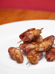 Rolls of slices of cooked bacon subject with a toothpick