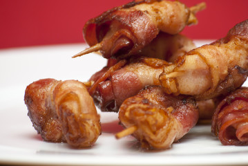 Rolls of slices of cooked bacon subject with a toothpick