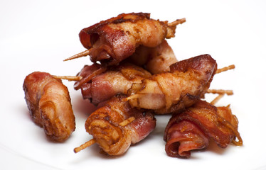 Rolls of slices of cooked bacon subject with a toothpick