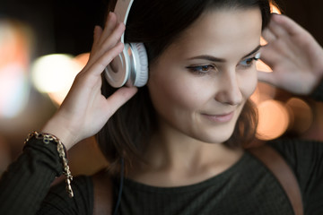 Fototapeta premium Young woman listening to music with headphones at night city