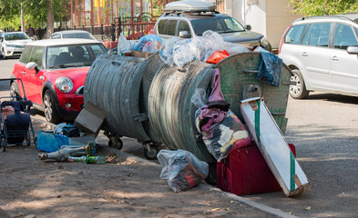 Garbage overfilled trash dumpsters in the street, surrounded by