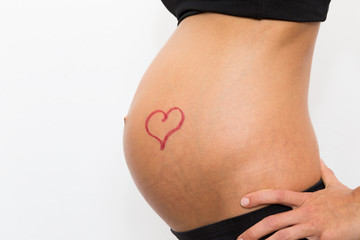 schwangere Frau hat ein Herz auf dem Bauch, es wurde aufgemalt