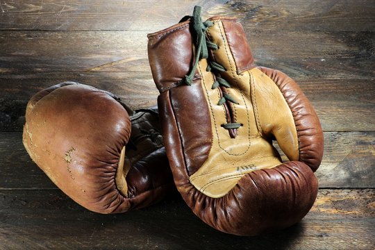 alte Boxhandschuhe auf rustikalem Holzhintergrund