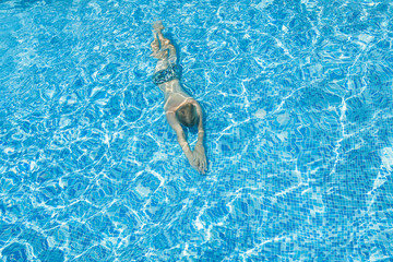 Silhouette of a person swiming in the pool.