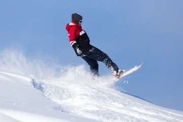 Jumping snowboarder from hill in winter
