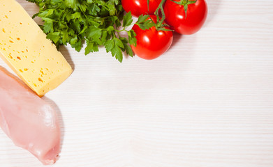 Food background of fresh chicken breast, cheese and tomato at the wooden board with copy space