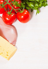 Food background of fresh chicken breast, cheese and tomato at the wooden board with copy space