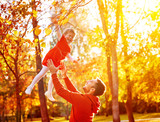 Happy family Dad throws child daughter up on walk in autumn