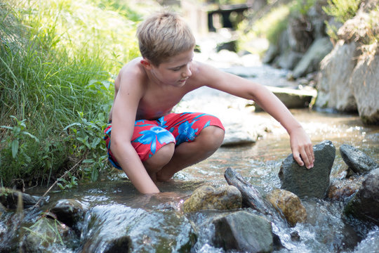 Junge baut im Bach einen Damm