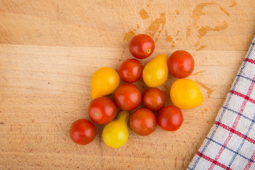 Red and yellow cherry tomatoes on a wooden cutting board