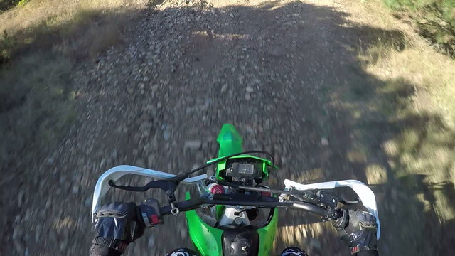 PoV: Enduro racer riding his offroad bike on dirt track climbing to the hill