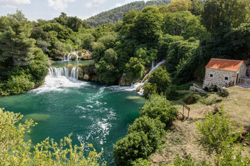 Scenic view of waterfalls, cascades and an old building at the Krka National Park in Croatia.