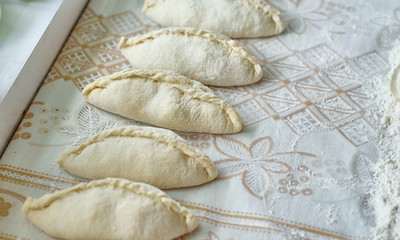 Kitchen, cooking pies with dough on the table
