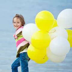 Fototapeta na wymiar girl walking in the beach with colored balloons 