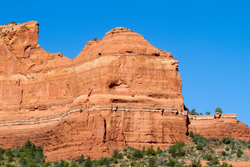 Fototapeta premium Massive red-rock cliffs, pines, and blue sky along Schnebly Hill Road near Sedona, Arizona