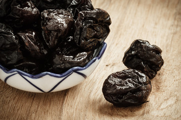 dried plums prunes in bowl on wooden table