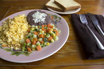 Huevo revuelto con frijol, pan y verduras
