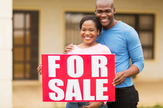 African American Couple Outside Home With For Sale Sign