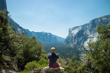 Fototapeta na wymiar Man looking at idyllic view of Yosemite National Park valley during summer vacation on perfect day with clear blue sky surrounded by lush greenery and mountains