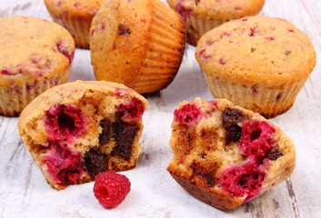 Fresh baked muffins with chocolate and raspberries on wooden background, delicious dessert
