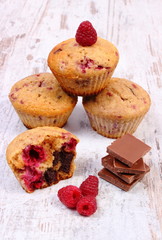Fresh baked muffins with raspberries and chocolate on wooden background, delicious dessert