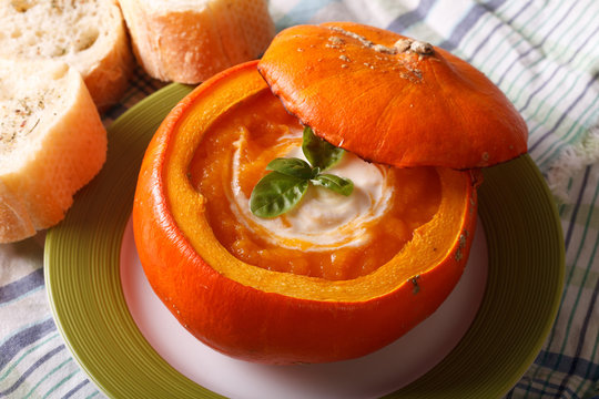 Delicious pumpkin soup with sour cream and basil close-up. horizontal
