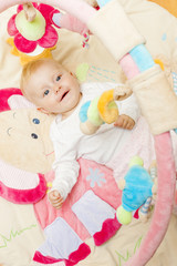 portrait of baby girl lying on playing mat