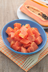 Ripe Papaya slices on a blue plate and wooden floor.