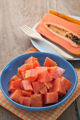 Ripe Papaya slices on a blue plate and wooden floor.