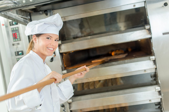 Female baker at bread oven