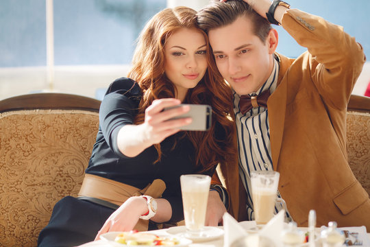 Young couple watching photos on mobile phone, sitting in a caf