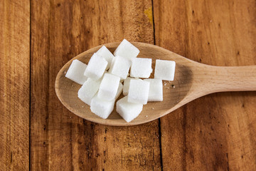 Sugar Cubes on Wooden Spoon over Wooden Background
