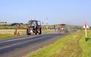Fototapeta premium Tractor mows grass on the side of road.