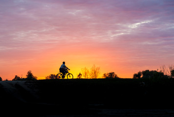 Fototapeta na wymiar Silhouette of a man on bike at sunset