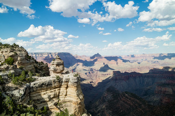 Man hiking overlooking epic view at the Grand Canyon National Park, Arizona, USA on a perfect Summer day with clear blue sky and puffy white clouds.