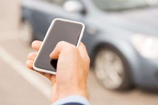 close up of man hand with smartphone and car